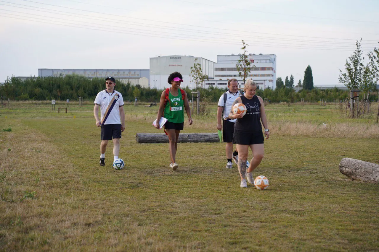 Spielerinnen und Spieler gehen mit ihren Fußbällen über die Fußballgolf-Anlage